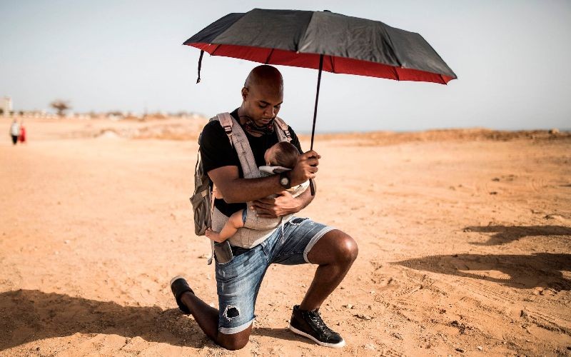 Alexis kneels with his baby at a protest in solidarity with the Black Lives Matter movement in Dakar, Senegal on June 9, 2020. (Photo by John Wessels/AFP Photo)